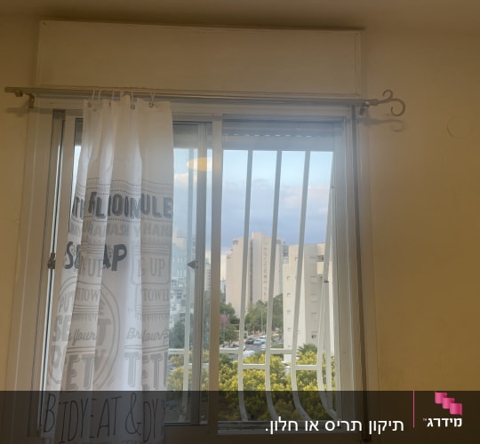 חלון עם וילון לבן ובריחי מתכת